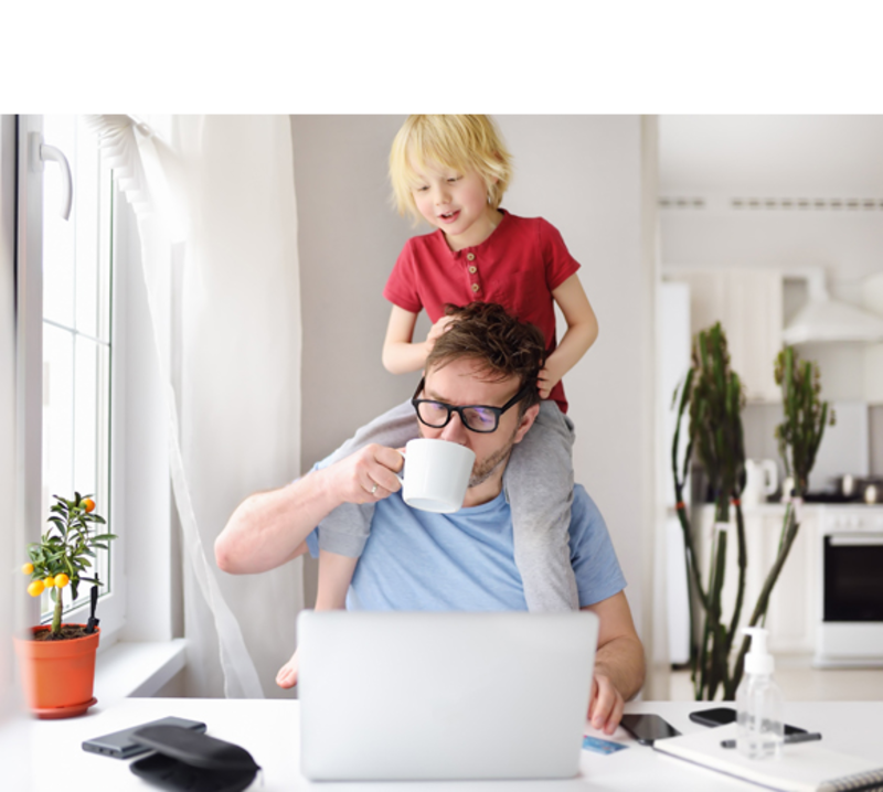 Mann arbeitet im Homeoffice mit Kind auf den Schultern