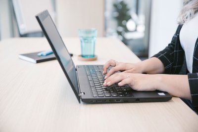 Laptop steht auf einem Tisch und jemand arbeitet daran
